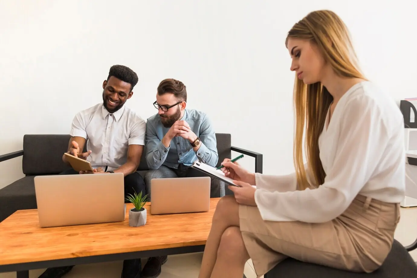 A woman taking notes near colleagues who are working